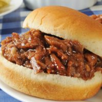 Closeup of a barbecue beef sandwich with macaroni salad and baked beans