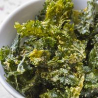 Close up color photo with delicious kale chips on white bowl, ready to enjoy a gourmet snack.
